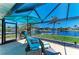 Screened patio with waterfront views and blue lounge chairs under a matching umbrella at 9404 Arnaz Cir, Port Charlotte, FL 33981