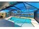 Screened in-ground pool and patio with canal view features an umbrella and lounge chairs at 9404 Arnaz Cir, Port Charlotte, FL 33981
