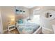 Cozy bedroom with a white bed, ocean-themed bedding, and natural light from the window at 9853 Bright Water Dr, Englewood, FL 34223