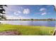 Scenic lake view with green lawn and landscaping under a clear blue sky with scattered clouds at 9853 Bright Water Dr, Englewood, FL 34223
