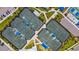 Aerial view showcasing well-maintained tennis courts with covered viewing areas and surrounding greenery at 9853 Bright Water Dr, Englewood, FL 34223