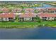 Aerial view of villas with tile roofs, screened lanais, and meticulous landscaping bordering a serene lake and golf course at 10805 Tarflower Dr # 101, Venice, FL 34293