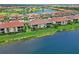 Aerial view showcases villas with tile roofs, screened lanais and impeccable landscaping near a lake and golf course at 10805 Tarflower Dr # 101, Venice, FL 34293