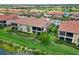 Aerial view of the villas featuring tile roofs, screened lanais and mature landscaping, situated by a lake and golf course at 10805 Tarflower Dr # 101, Venice, FL 34293