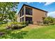 Two-story home showcasing a screened balcony overlooking a well-maintained lawn with mature shrubs and trees at 10805 Tarflower Dr # 101, Venice, FL 34293