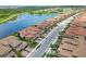 Aerial view of community homes along a road and lake, featuring terra cotta roofs, garages, and mature landscaping at 10805 Tarflower Dr # 101, Venice, FL 34293