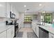 Bright kitchen features white cabinets, stainless steel appliances, and tile backsplash, offering modern style and functionality at 10805 Tarflower Dr # 101, Venice, FL 34293