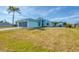 Exterior elevation of a light blue home featuring a two-car garage, palm tree, and lawn at 12359 Deepwoods Ave, Port Charlotte, FL 33981