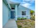 Close up of the front exterior featuring a light blue home with a blue front door and manicured landscape at 12359 Deepwoods Ave, Port Charlotte, FL 33981