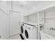 Laundry room with modern washer and dryer, shelving, sink and access to the backyard at 12359 Deepwoods Ave, Port Charlotte, FL 33981