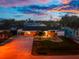Charming single-story home with a well-manicured lawn and vibrant landscaping, enhanced by twilight lighting at 1245 Gulf Blvd, Englewood, FL 34223