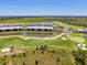 An aerial view of a golf course community with a swimming pool and clubhouse next to a pond at 12470 Wellen Golf St # 207, Venice, FL 34293