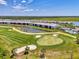 An aerial view of a golf course community with a swimming pool and clubhouse next to a pond at 12470 Wellen Golf St # 207, Venice, FL 34293