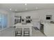 Well-lit, modern kitchen featuring white cabinets, an island with seating, and stainless steel appliances at 12470 Wellen Golf St # 207, Venice, FL 34293