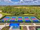 Aerial view of well-maintained tennis courts with beautiful landscaping and a shaded seating area at 12470 Wellen Golf St # 207, Venice, FL 34293
