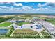 Expansive aerial view of a baseball stadium, multiple sports fields, and ample parking amidst a picturesque landscape at 12470 Wellen Golf St # 208, Venice, FL 34293