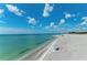 Picturesque beach with clear turquoise water, white sand, and a blue umbrella under a beautiful blue sky and white clouds at 12470 Wellen Golf St # 208, Venice, FL 34293