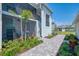 Exterior view of condo with brick pathway leading to screened patio, with manicured landscaping at 12470 Wellen Golf St # 208, Venice, FL 34293