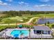 Aerial view of a community pool, lounge area and shade pavilion with a golf course and pond in the background at 12470 Wellen Golf St # 208, Venice, FL 34293