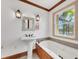 Bathroom with a soaking tub, pedestal sink, and window overlooking the backyard at 1275 Bayshore Dr, Englewood, FL 34223