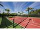 Well-maintained tennis court surrounded by palm trees under a clear blue sky at 13113 Gasparilla Rd # A503, Placida, FL 33946