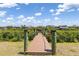 Wooden dock with rope railing leading to canal homes under a bright blue, partially cloudy sky at 14556 Gaspar Loop, Port Charlotte, FL 33981