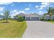 Charming home showcasing a well-maintained lawn, palm trees and a paver driveway at 14556 Gaspar Loop, Port Charlotte, FL 33981