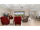Open-concept living room with tile flooring, tray ceiling, fan, and a backyard view at 14556 Gaspar Loop, Port Charlotte, FL 33981