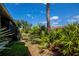 Private backyard with mature landscaping, including palms and flowering plants, with clear blue skies above at 148 Jose Gaspar Dr # 148, Englewood, FL 34223