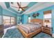 This is the main bedroom with a tropical beachy theme, offering patio access, light blue walls, and a ceiling fan at 15674 Applewhite Cir, Port Charlotte, FL 33981