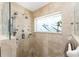 A modern shower with travertine tile, multiple shower heads, and decorative privacy window at 158 Morgan Se Ln, Port Charlotte, FL 33952