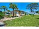 Backyard of home with green grass, tropical landscaping, and utility shed at 1585 Poinciana Rd, Venice, FL 34293