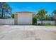 A detached garage with a large garage door and ample driveway space and tropical landscaping at 1585 Poinciana Rd, Venice, FL 34293