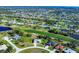 Expansive aerial view of a residential neighborhood with golf course and pond, highlighting community living and lush green spaces at 27 Tee View Rd, Rotonda West, FL 33947