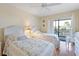 Bright bedroom features twin beds, a ceiling fan, dresser, and balcony access with lush scenery at 2769 N Beach Rd # 205, Englewood, FL 34223