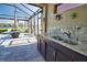 Screened-in patio featuring a built-in outdoor kitchen with a sink and grill at 35 Medalist Rd, Rotonda West, FL 33947