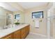Well lit bathroom with double sinks, wooden cabinets, and plenty of storage with the adjacent shelves at 39 Bunker Pl, Rotonda West, FL 33947