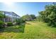 Expansive backyard featuring a lush green lawn, mature trees, and a screened lanai at 4004 Landor Ct, Venice, FL 34293