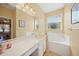 Bright bathroom featuring double sink vanity, soaking tub, and decorative light fixture at 4004 Landor Ct, Venice, FL 34293