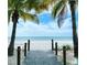 Tranquil beach access with a wooden boardwalk, framed by palm trees, leading to the ocean at 4004 Landor Ct, Venice, FL 34293