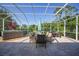 Large, screened-in lanai featuring a hot tub, dining area, and picturesque backyard views at 4004 Landor Ct, Venice, FL 34293