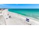 Aerial view of a stunning white sand beach with turquoise water and sun umbrellas along the shoreline at 5000 Gasparilla Rd # 23A, Boca Grande, FL 33921