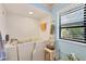 A view of the bathroom with tiled walls, walk-in tub, towel rack, small table, and a window at 521 Artists Ave, Englewood, FL 34223