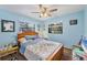 A view of the bedroom with blue walls, ceiling fan, carpet floors, and two windows at 521 Artists Ave, Englewood, FL 34223