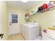 Bright laundry room features a white washer and dryer, utility sink, and a wire rack shelf for storage at 68 Long Meadow Ln, Rotonda West, FL 33947