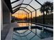 A serene screened-in pool area highlights sunset views and a comfortable lounge space at 725 Clearview Dr, Port Charlotte, FL 33953