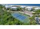 Aerial view of a tennis court surrounded by tropical foliage and neighboring condos with ocean view at 7470 Palm Island Dr # 2813, Placida, FL 33946