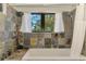 Bathroom with a bathtub, shower, large window with nature views, and slate-style tile at 760 S Oxford Dr, Englewood, FL 34223