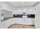 Bright kitchen featuring white cabinetry, stainless steel appliances, dark backsplash, and modern light-colored wood flooring at 821 Montrose Dr # 201, Venice, FL 34293