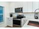 Close up of a kitchen featuring stainless steel appliances and bright white cabinets and backsplash at 8413 Placida Rd # 205, Placida, FL 33946
